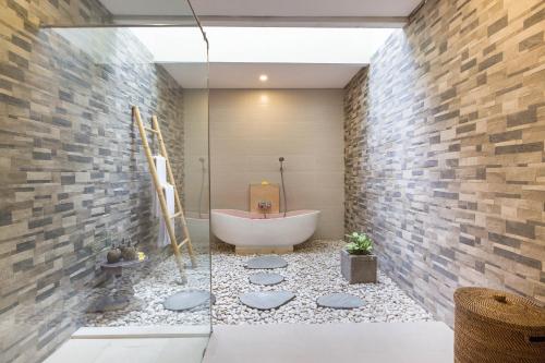 a bathroom with a bath tub and a shower at Villa Atap Padi by Nagisa Bali in Ubud