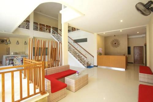 a living room with stairs and a red bench at Kuta Suci Guesthouse in Kuta