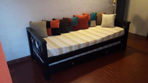 una cama de madera con muchas almohadas. en Barracuda 7 en Santa Teresita