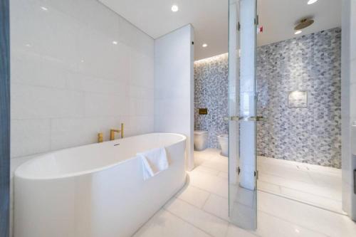 La salle de bains blanche est pourvue d'une baignoire et d'une douche. dans l'établissement *Five Palm* 2bdr Private Beach, à Dubaï