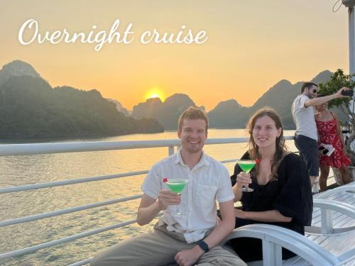 a man and a woman sitting on a boat with drinks at BBQ HOSTEL in Ha Long