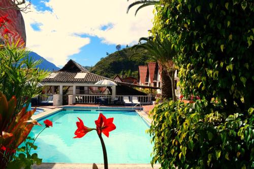 a pool at a resort with a red flower in the foreground at Hosteria Casa Giralda in Baños