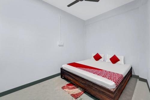 OYO Flagship YUVRAJ Hotel في باتنا: سرير مع وسائد حمراء في غرفة بيضاء