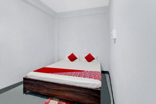 1 cama con almohadas rojas en una habitación blanca en OYO Flagship YUVRAJ Hotel, en Patna