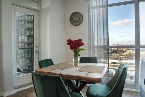 a dining room table with green chairs and a vase of flowers at Downtown Toronto Condo Parking Sleeps 4 Balcony Walk to Lake in Toronto