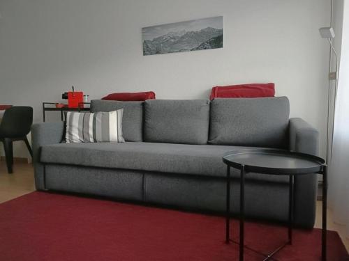 - un salon avec un canapé gris et une table dans l'établissement Ferienwohnung Falknis in Maienfeld mit Blick auf die Berge - b48844, à Maienfeld