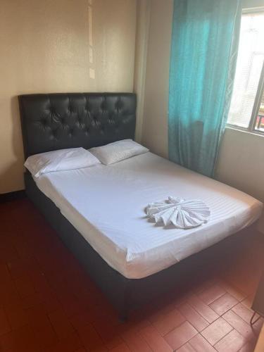 a bed with a black headboard and white sheets at Nuevo hospedaje benny in Melgar