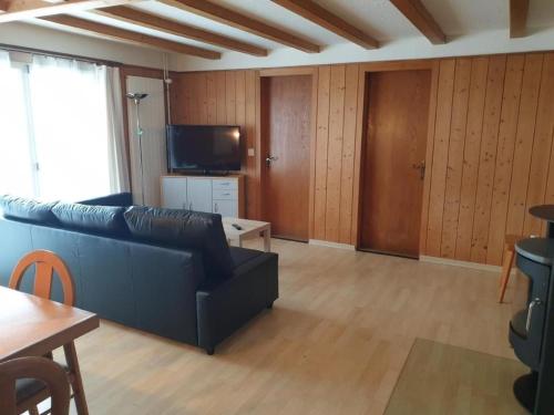 uma sala de estar com um sofá e uma televisão em Ferienwohnung Saturn - b48834 em Sörenberg