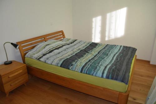 um quarto com uma cama com uma cabeceira em madeira e uma mesa em Schmucke ruhige 25 Parterre Wohnung - b48866 em Nottwil