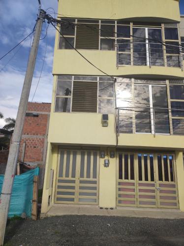 een geel huis met twee garagedeuren en een paal bij Apartamento turístico portal del prado in Santa Rosa de Cabal