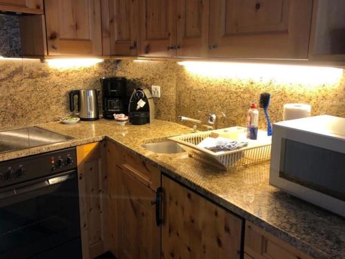 eine Küchentheke mit einer Spüle und einer Mikrowelle in der Unterkunft Chesa Trafögl - b48847 in Pontresina
