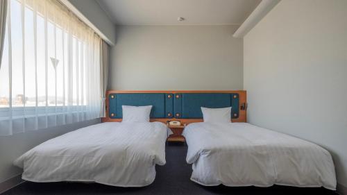 two beds sitting next to each other in a room at Hotel Global View Tsuchiura in Tsuchiura