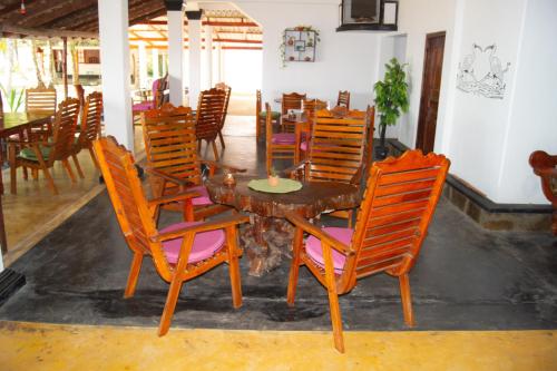 a dining room with a wooden table and chairs at Ibisbird Beach Bungalows, Sport, Spa and Restaurant in Tangalle