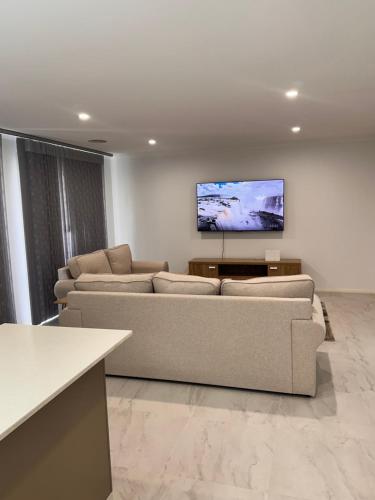 a living room with couches and a flat screen tv at Canberra 3 Bedroom home to remember in Harrison