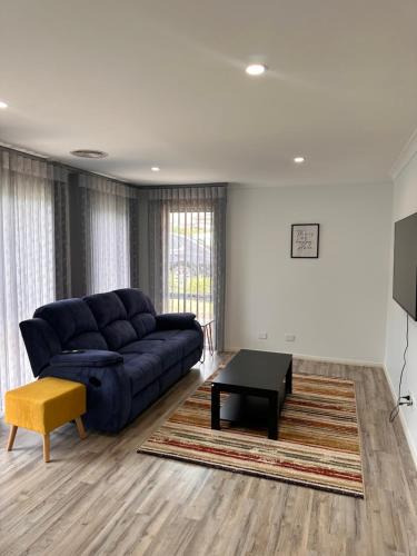 a living room with a blue couch and a table at Canberra 3 Bedroom home to remember in Harrison