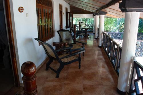 a hallway with chairs and tables on a porch at Ibisbird Beach Bungalows, Sport, Spa and Restaurant in Tangalle