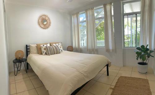 a bedroom with a bed with white sheets and windows at Tree Escape in Rainbow Beach