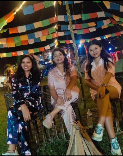 three women sitting in chairs under a tent at TEC Resort and bar in Dharān Bāzār