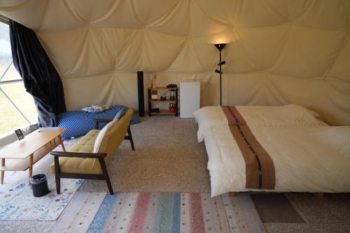 um quarto com uma cama e uma cadeira numa tenda em ASOBI HACK 