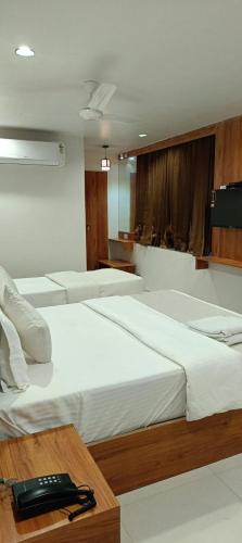 een kamer met drie bedden en een telefoon op een tafel bij Hotel Royal Relax in Gandhinagar