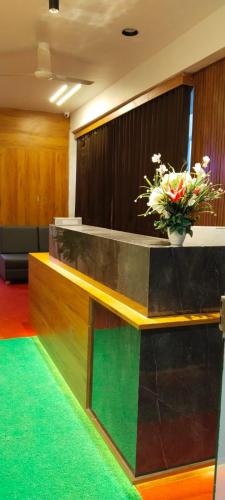 a lobby with a reception desk with a vase of flowers at Hotel Royal Relax in Gandhinagar
