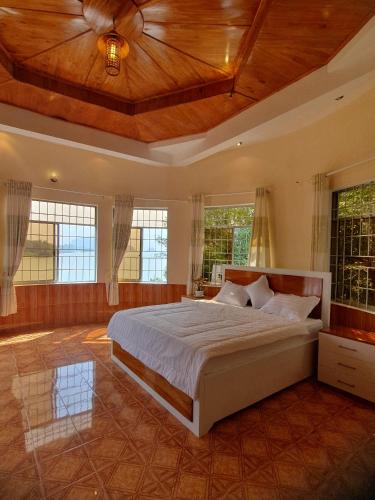 a bedroom with a large bed with a wooden ceiling at Green Hill Guest House in Ba Hòn