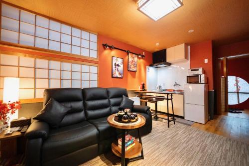 a living room with a black leather couch and a kitchen at ゼロイン祇園三条 in Kyoto