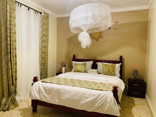1 dormitorio con 1 cama grande y lámpara de araña en Muggiez Olive, Kira en Kampala