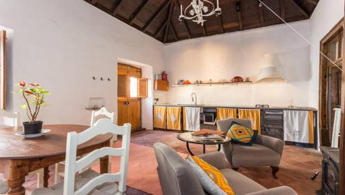 a living room with a table and a kitchen at Casa do Levante in Olhão
