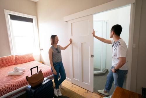 un hombre y una mujer de pie en una habitación con una puerta en YHA Port Elliot Beach House, en Port Elliot