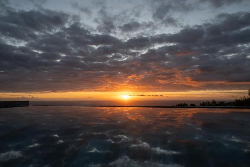 einen Sonnenuntergang über einem Wasserkörper mit Sonnenuntergang in der Unterkunft La VILLA MAHOT in Petite Île