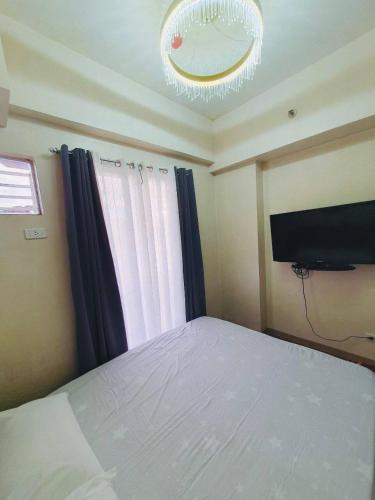 a bedroom with a bed and a flat screen tv at BAGUIO CONDO TRANSIENT MOLDEX RESIDENCES by DEI GRATIA in Baguio