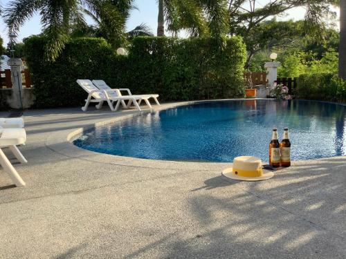 two bottles of wine sitting next to a swimming pool at แกรนด์ฮิลล์ เฮาส์ Grandhill house in Hua Hin