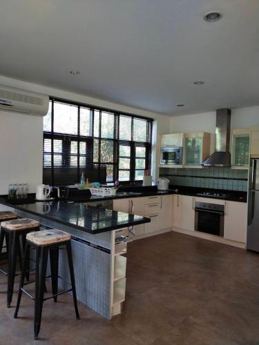 a kitchen with a counter and some stools in it at แกรนด์ฮิลล์ เฮาส์ Grandhill house in Hua Hin