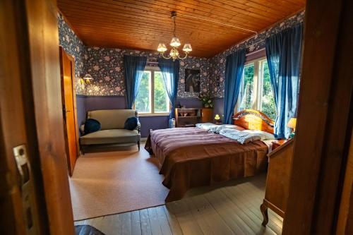 a bedroom with a bed and a chair and windows at Grannys cottage in Laihia