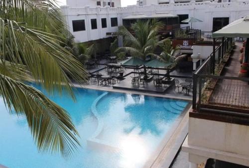 een groot zwembad met tafels en stoelen in een gebouw bij Hotel Aarya Grand in Sarkhej