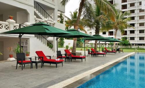 een groep stoelen en parasols naast een zwembad bij Hotel Aarya Grand in Sarkhej