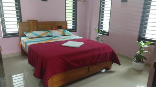 um quarto com uma cama com um cobertor vermelho em 2BHK- RoyalPlaza Appartments, Kalpetta, Wayanad A3 em Kalpetta