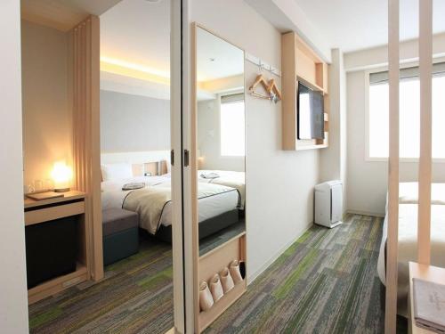 京都市にあるアーバンホテル京都五条プレミアムのベッドと鏡が備わるホテルルーム