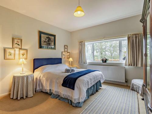 - une chambre avec un lit doté d'une tête de lit bleue et d'une fenêtre dans l'établissement 4 Bed in Uckfield BT021, à Buxted