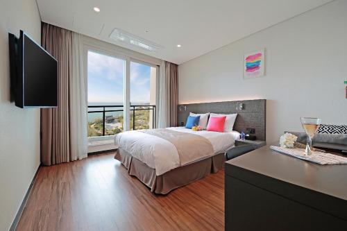 a bedroom with a bed and a large window at Airsky Hotel Incheon in Incheon