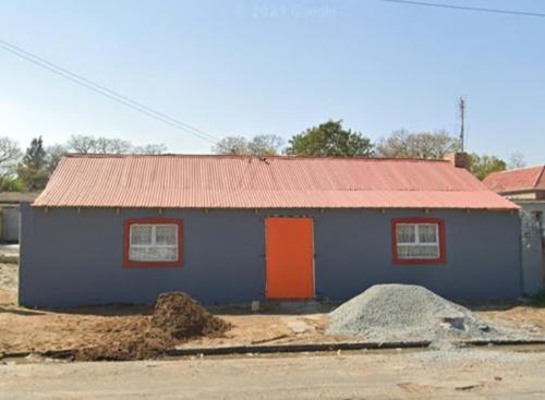 un edificio azul con una puerta naranja y un techo rojo en Edge guest room. en Macleantown