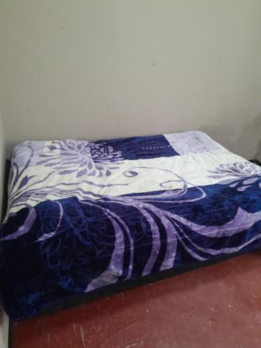 Una cama con una manta azul y blanca. en Edge guest room. en Macleantown