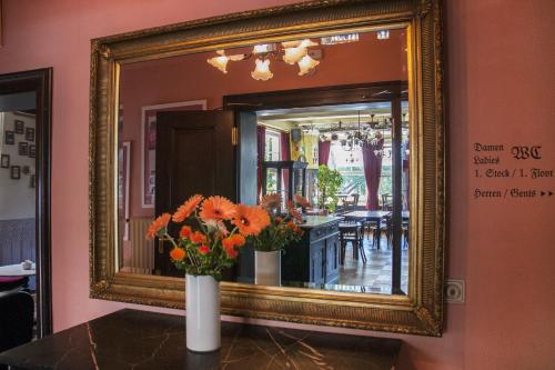 a vase of flowers in front of a mirror at Hajo´s Germania Lodge & Irish Pub in Rüdesheim am Rhein