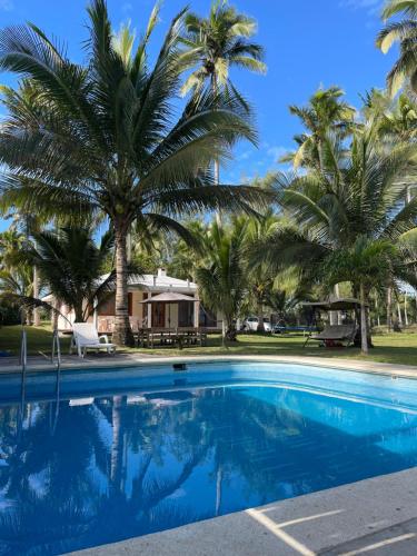 a swimming pool with palm trees and a house at Vikinga casa de playa in Monte Gordo