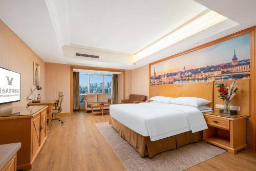 1 dormitorio con 1 cama blanca grande y escritorio en Vienna International Hotel Wuhan Jiefang Avenue, en Wuhan