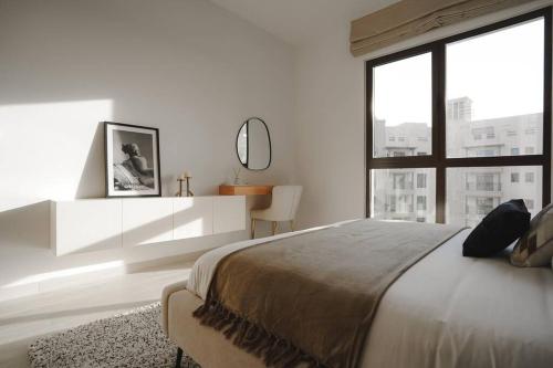 a white bedroom with a large bed and a window at Brand New l Stylish and Spacious 2BR in Madinat Jumeirah in Dubai