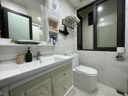 a white bathroom with a sink and a toilet at Dahlia Homestay Tay Ho in Hanoi