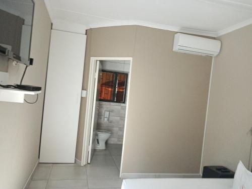 a bathroom with a toilet and a window at Upi guesthouse in Otjiwarongo