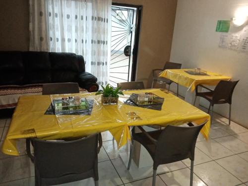 two tables with yellow table cloths on them in a living room at Upi guesthouse in Otjiwarongo